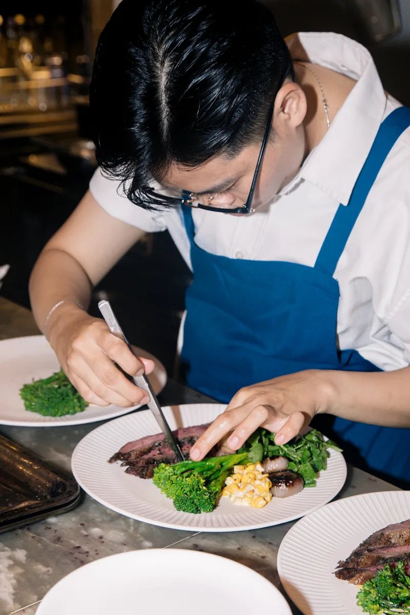 Chef plating a Picanha Rump steak with broccoli and sides at MUOI Bistro