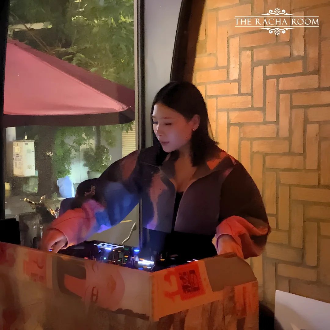 Female DJ performing behind a DJ controller at The Racha Room