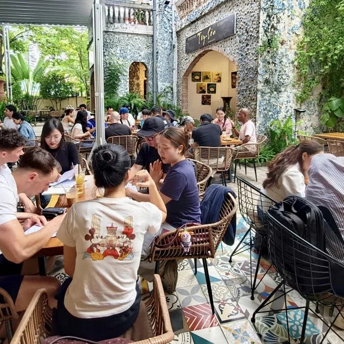 Language exchange participants seated around tables in a cafe courtyard; illustrative event-page photo, not proof of this date.