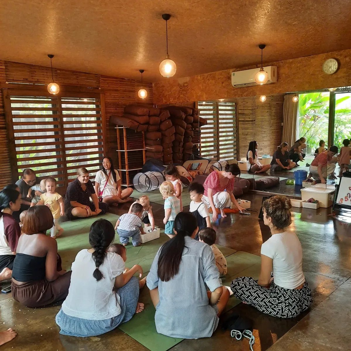 Parents and toddlers sitting on mats at an Anh's Playgroup session in the Yoga Pod studio