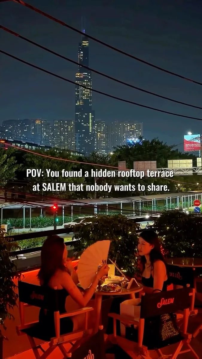 Guests on the terrace at Salem Social House, with the venue’s branded chairs and the Saigon skyline at night.